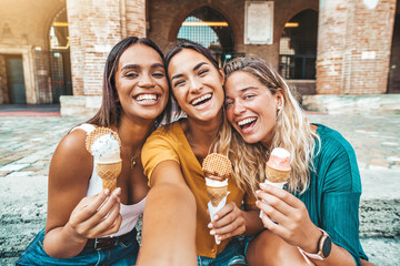 Happy group of women eating ice cream cones walking on city street