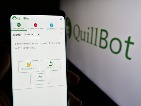 Stuttgart, Germany - 03-12-2024: Person holding mobile phone with web page of US artificial intelligence writing company QuillBot with logo. Focus on center of phone display.