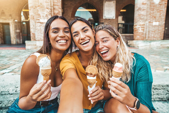 Fototapeta Happy group of women eating ice cream cones walking on city street