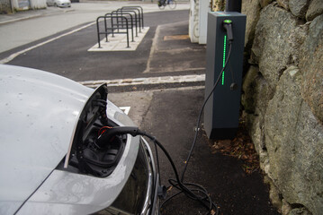 A green electric car is plugged into a charging station, showcasing the ease of recharging