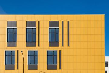 Yellow ventilated facade of building wall with windows and decorative finishes. Fragment of office building. Architectural or building background. Copy space