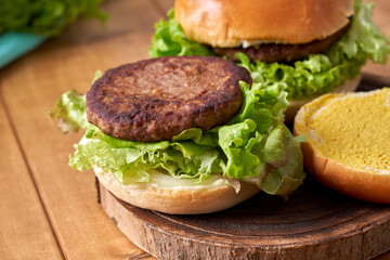 Delicious hamburger with green salad on a wooden table.