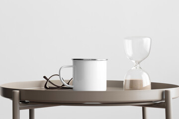 Enamel mug mockup with a sand clock decoration on the beige table.