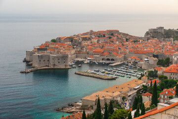 Aerial view of Dubrovnik Old town with turquoise water harbor on Adriatic sea at sunset, Dalmatia, Croatia. Medieval fortress with boats and yachts in marina on the sea coast