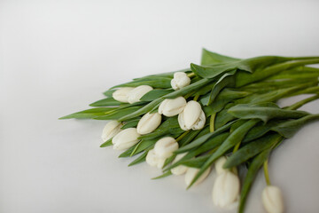 Bouquet of white tulips on the right on a white background. Top view. Copy space. Wedding flowers. 