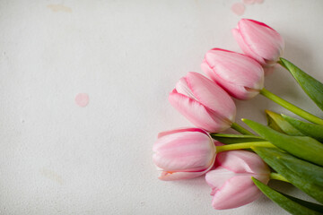 A bouquet of pink tulips and pink tinsel on a white background in the upper right corner. Copy space. View from above.