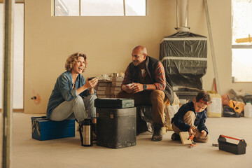 Mom and dad enjoying a relaxing snack break during a family home renovation project with their son