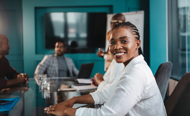 Happy business woman sitting in a corporate boardroom meeting with coworkers - obrazy, fototapety, plakaty