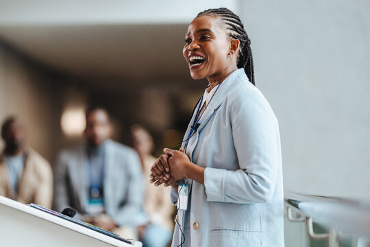 Young African businesswoman speaking at a conference with colleagues in background