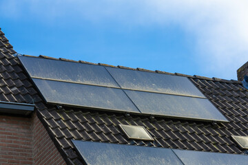 Fototapeta premium Utrecht, the Netherlands. 14 March 2024. Dirty solar panels on a family house integrated on the roof. View of solar panels with dirt (solar cell) on the roof of a house
