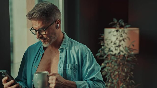 Confident senior man with a cup of coffee, displaying a relaxed attitude in a cozy home setting in the morning.