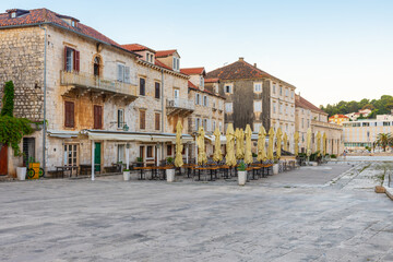Main square Pjaca in old medieval town Hvar with outdoors restaurants and side walk cafe at sunrise with nobody, Dalmatia, Croatia. Popular travel and tourist destination on summer vacations - 761781720