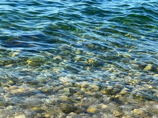 Blue rippled sea water with pebbles at the bottom