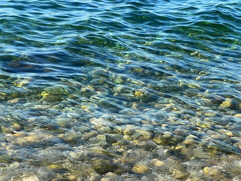 Blue rippled sea water with pebbles at the bottom
