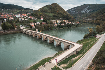 Old Ottoman type bridge on a river with hills in background, river Drina in Visegrad