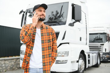 Man trucker talking on the phone by his white truck