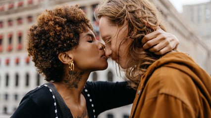 Affectionate couple sharing a tender kiss on city street - obrazy, fototapety, plakaty