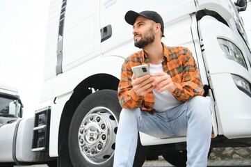 Man trucker talking on the phone by his white truck
