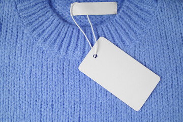 Blank clothing tag and inner label on neck of blue knitted sweater background. Mockup, template...