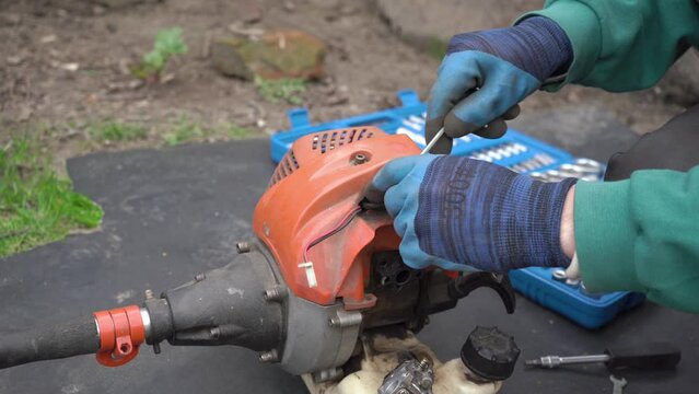 unscrew the spark plug in the brush cutter, remove the spark plug from the brush cutter, the man replaces the spark plug on the brushcutter