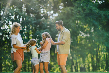 A happy parents playing with their daughters in nature.