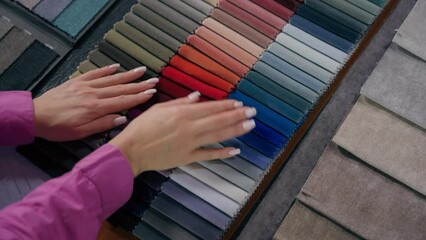 Top view female hands arms touch soft velvet cloth samples eco natural materials in shop woman designer choosing color tone fabric selection colorful catalog textile buying shopping in fashion atelier