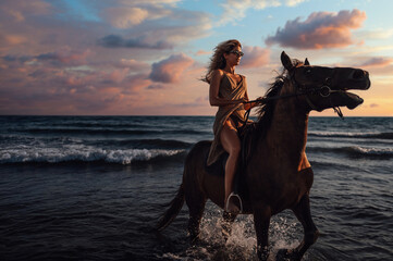 A young attractive woman is horseback riding at seaside at sunset.