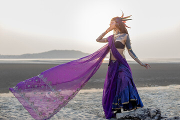 a woman in a purple and blue dress is standing on a beach