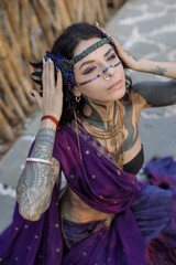 a woman with a lot of tattoos on her body is wearing a purple saree