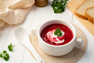 Easy beetroot soup with sour cream,creamy soup in a white bowl.