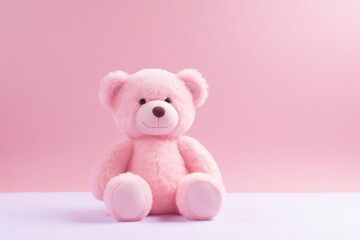 a pink teddy bear sitting on a white surface