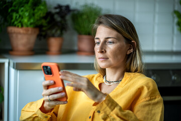 Relaxed interested female reading messages in mobile phone enjoy communication. Dreaming woman looking at cellphone screen thoughtfully chatting, scrolling web, surfing social media, online shopping.