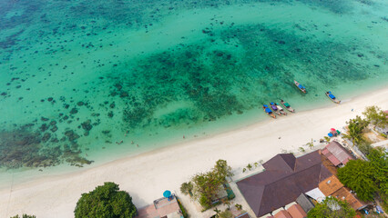 Aerial view of traditional Thai long tail boats at a beach at Koh Phi Phi island, Krabi, Thailand. Tropical paradise white sand beach with no people, turquoise waters of Andaman sea. 