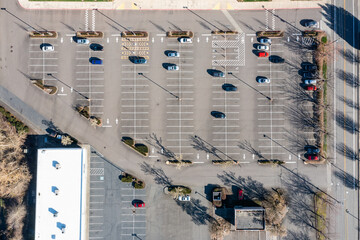 Aerial drone view of a half-empty car parking lot near shopping centers