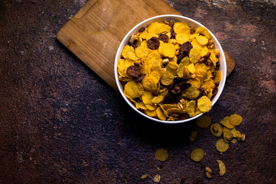 Crispy flakes for breakfast in white bowl on wooden background. Selective focus.