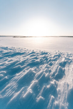 Winterzauber bei Sonnenuntergang: Unberührte Schneelandschaft mit schimmernden Wehen und strahlendem Licht