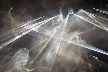 Laser beams intersecting in a haze of smoke to reveal diffraction patterns.