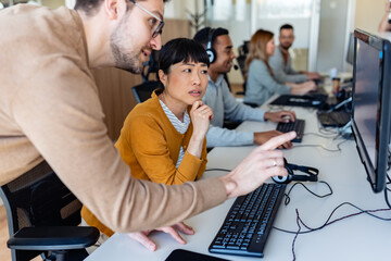 In their office, a multi-ethnic group of IT professionals works together, collaborating and using computers to accomplish their tasks