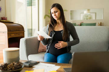 Stressed pregnant woman with a lot of debt looking worried