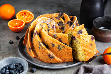 Orange Blueberry Bundt Cake with poppy seed and icing. Homemade bakery. Fresh fruits on background....