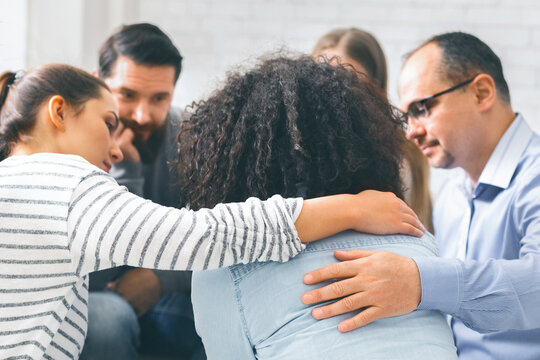 Addicted people comforting upset woman at therapy session