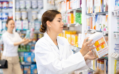 Young woman pharmacist distributes assortment of goods on counter in pharmacy