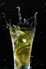 黒い背景の前でグラスに入ったレモンミント水が水しぶきを上げている