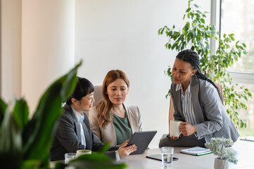 A diverse group of multi-ethnic businesswomen sit in the office and have a conversation. They engage in discussions, reflecting their entrepreneurial spirit and collaboration