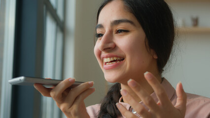 Close up Arabian woman record voice message on speaker phone talking use loudspeaker microphone recording voicemail speaking with AI mobile assistance Indian girl businesswoman talk cellphone at home