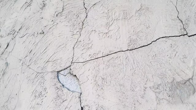 Cracked plaster. Damaged plastered, concrete wall in chips, cracks.