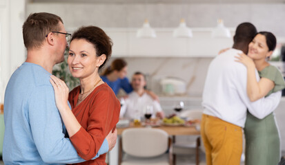 Multiethnic male and female couples slow dancing in kitchen