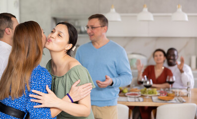Pleased host and hostess meeting their friends during get-together at comfortable home atmosphere