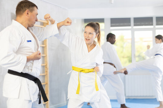 Adult man and adult woman judokas practicing judo technique in group in gym