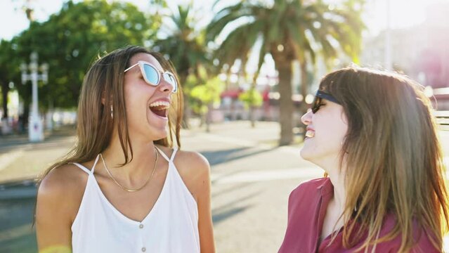 Two young women friends laughing together enjoying a sunny summer day during their holiday trip. Concept of travel, holidays and friendship